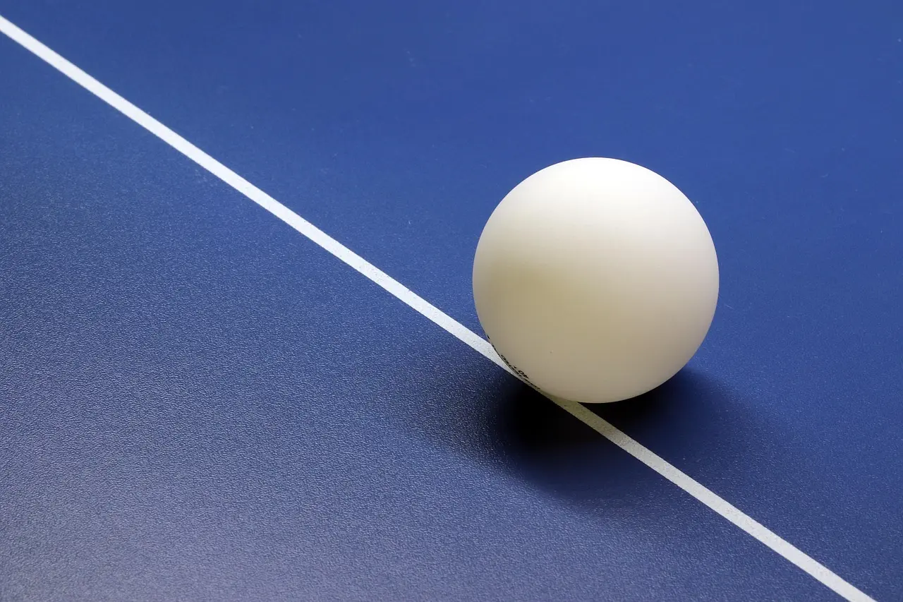 Bordtennisbold på et blåt bord med en hvid linje